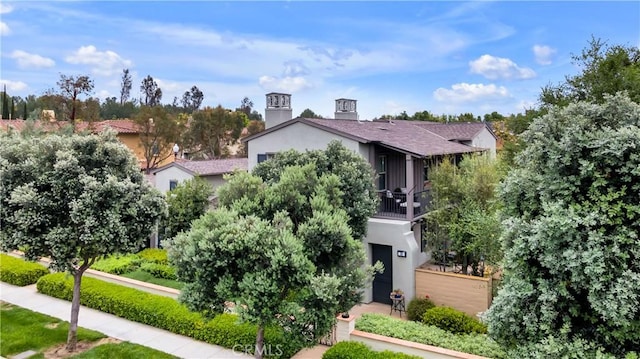 38 Upperbend, Irvine, CA 92618 - obstructed view of property featuring a balcony, stucco siding, a chimney, and fence