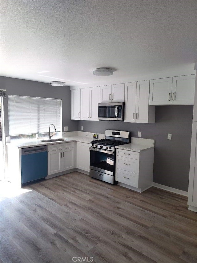 26702 Via Linares, Mission Viejo, CA 92691 - kitchen with stainless steel appliances, a sink, white cabinets, a textured ceiling, and wood finished floors
