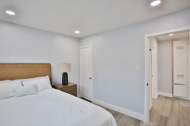 bedroom featuring light wood finished floors, recessed lighting, baseboards, and a closet
