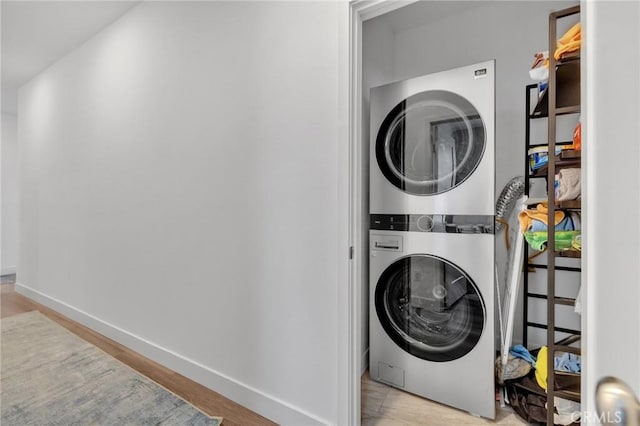 laundry area with estacked washer and dryer and baseboards