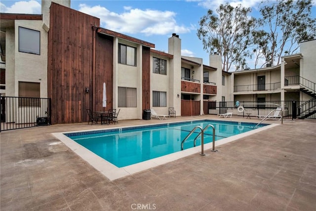 community pool with fence and a patio area