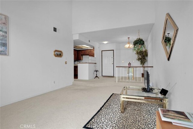 hall with carpet flooring, a chandelier, and an upstairs landing