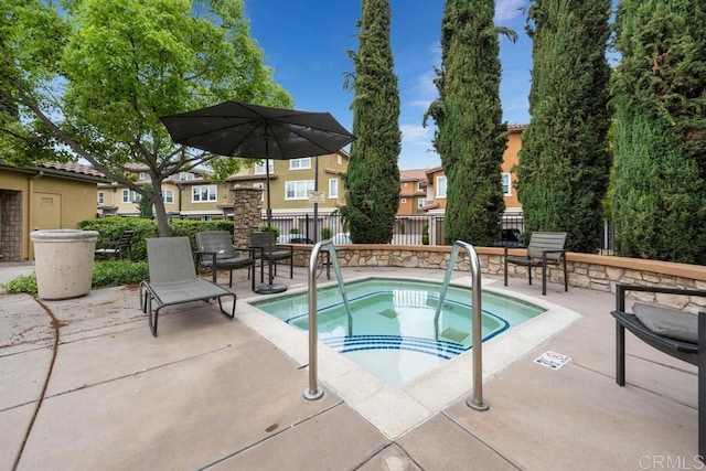 view of swimming pool with a hot tub, fence, a patio, and a residential view
