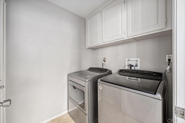 washroom with cabinet space, washing machine and dryer, light tile patterned flooring, and baseboards