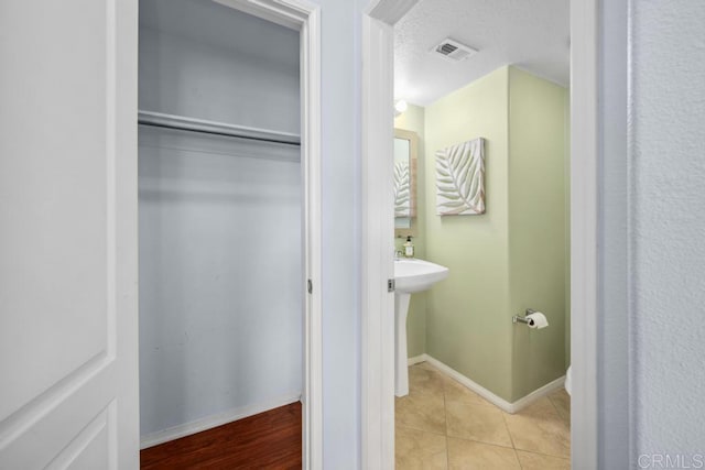 bathroom featuring baseboards, tile patterned flooring, and a textured ceiling
