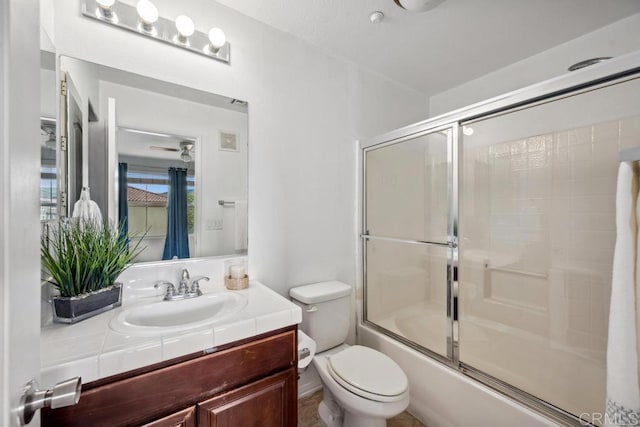 bathroom with toilet, vanity, and bath / shower combo with glass door