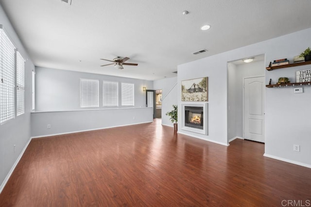 unfurnished living room featuring a ceiling fan, wood finished floors, a glass covered fireplace, baseboards, and recessed lighting