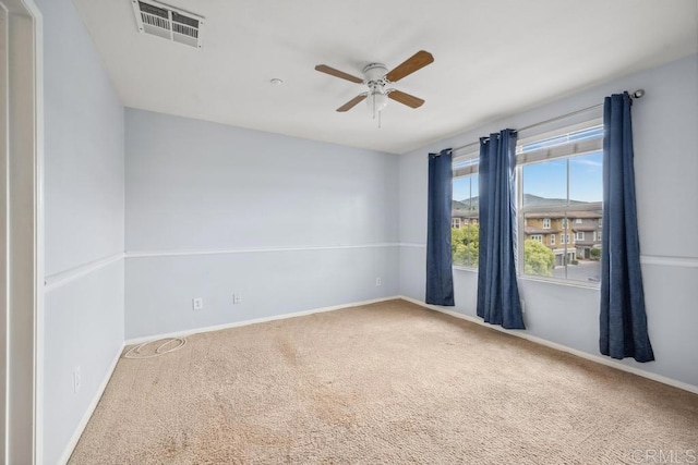 carpeted spare room featuring a ceiling fan and baseboards