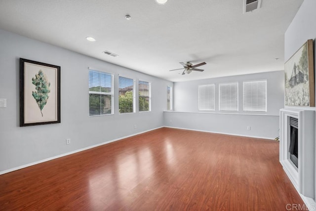 unfurnished living room featuring ceiling fan, wood finished floors, a glass covered fireplace, baseboards, and recessed lighting