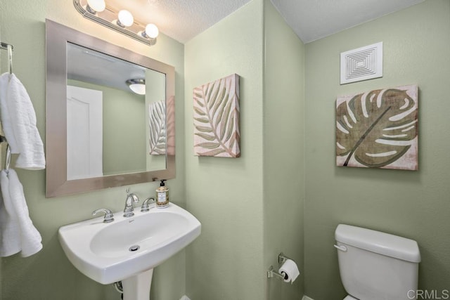 bathroom with a sink, toilet, and a textured ceiling
