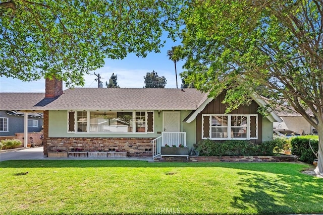 view of front of property with a chimney, a front lawn, brick siding, roof with shingles, and stucco siding