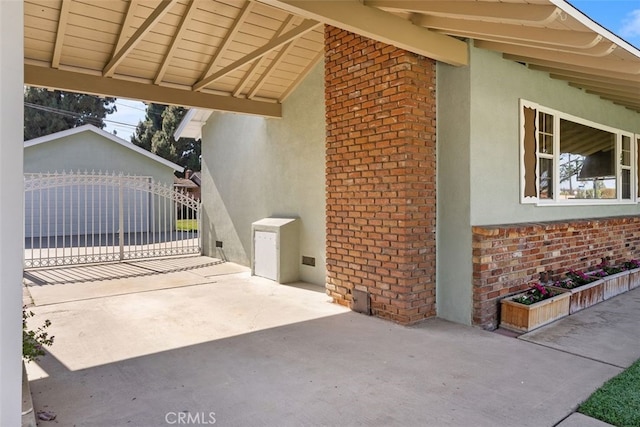 view of side of property featuring stucco siding, brick siding, and an outdoor structure
