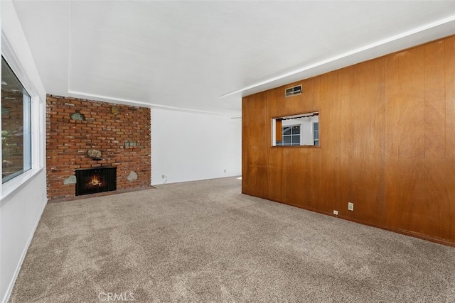 unfurnished living room featuring carpet floors and a brick fireplace