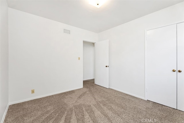 unfurnished bedroom featuring carpet floors, baseboards, and a closet