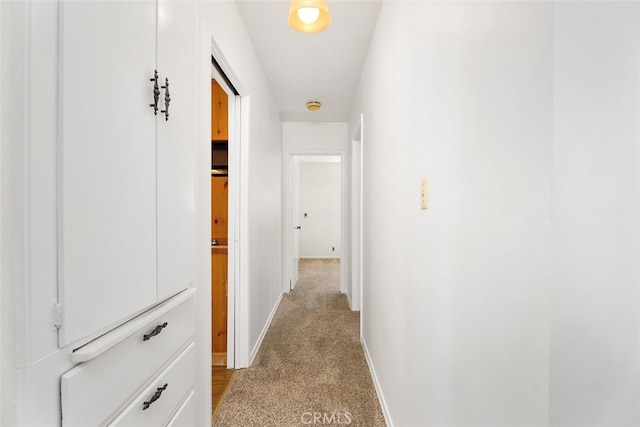 hallway featuring baseboards and light colored carpet