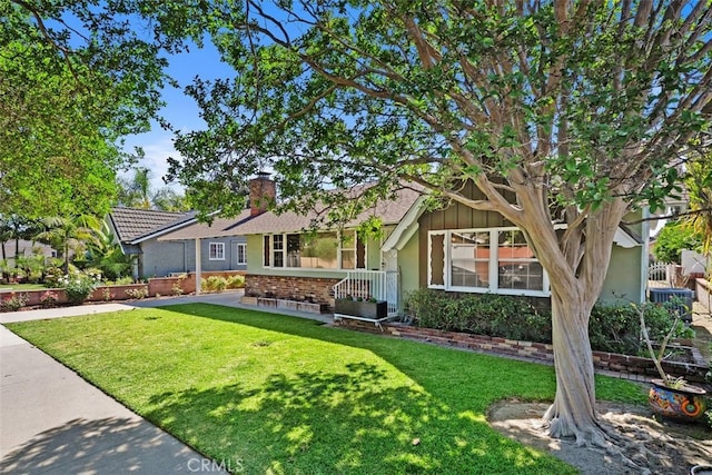 view of front of property featuring a front lawn, a chimney, and brick siding