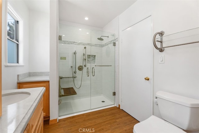 full bath with toilet, a shower stall, wood finished floors, vanity, and recessed lighting