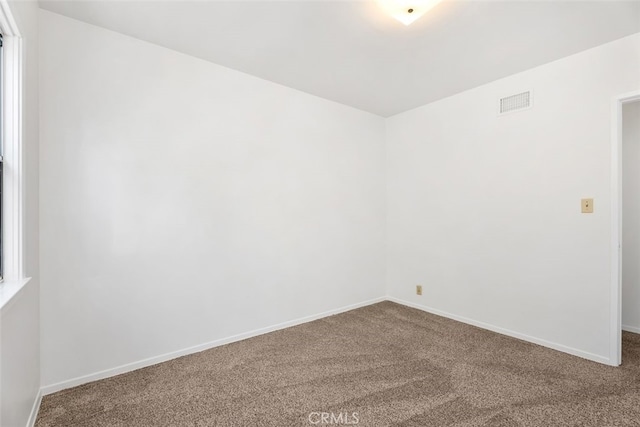empty room featuring carpet flooring and baseboards