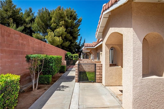 43473 30th St W Unit 4, Lancaster, CA 93536 - view of home's exterior with stucco siding, a gate, fence, and a tiled roof