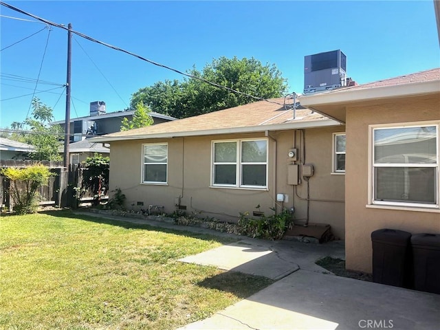 view of side of property with stucco siding, a shingled roof, central air condition unit, and a patio
