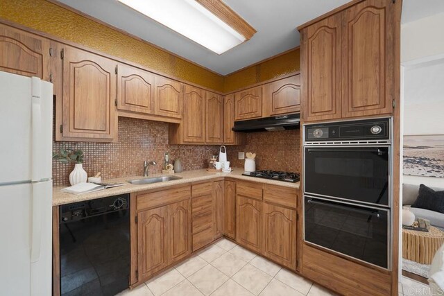 5426 Dwight St, San Diego, CA 92105 - kitchen featuring black appliances, under cabinet range hood, light countertops, backsplash, and light tile patterned floors