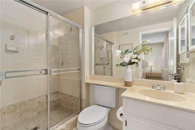 full bathroom featuring a stall shower, toilet, and vanity