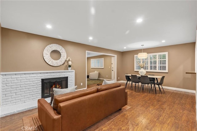 living room with a brick fireplace, recessed lighting, wood finished floors, and baseboards