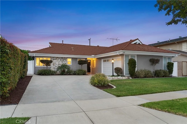 ranch-style home featuring a tiled roof, stucco siding, a garage, a lawn, and driveway