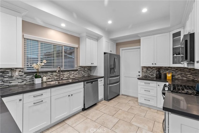 kitchen with stainless steel appliances, a sink, backsplash, white cabinets, and dark countertops