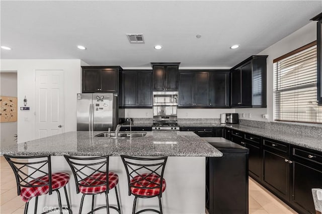 37732 Phelan Ln, Palmdale, CA 93552 - kitchen with stainless steel appliances, a sink, an island with sink, dark cabinetry, and dark stone counters