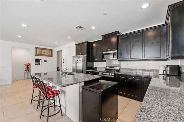 37732 Phelan Ln, Palmdale, CA 93552 - kitchen featuring appliances with stainless steel finishes, stone counters, a sink, a breakfast bar, and a kitchen island with sink