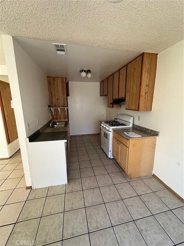 1102 Monroe St, Lake Elsinore, CA 92530 - kitchen featuring white gas stove, dark countertops, light tile patterned floors, and a textured ceiling