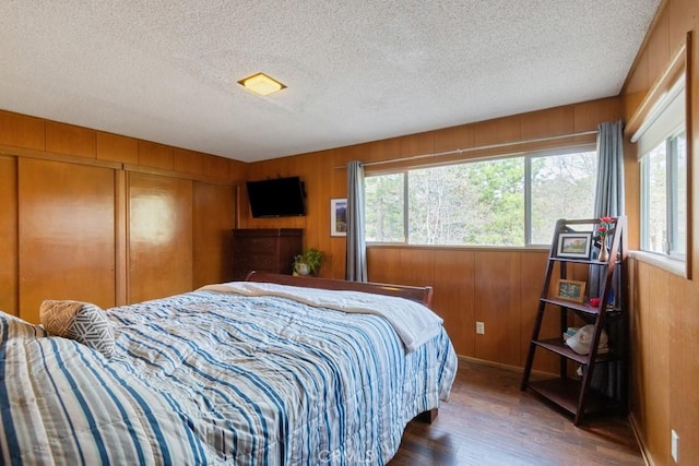 bedroom featuring wood finished floors, a textured ceiling, a closet, and wooden walls