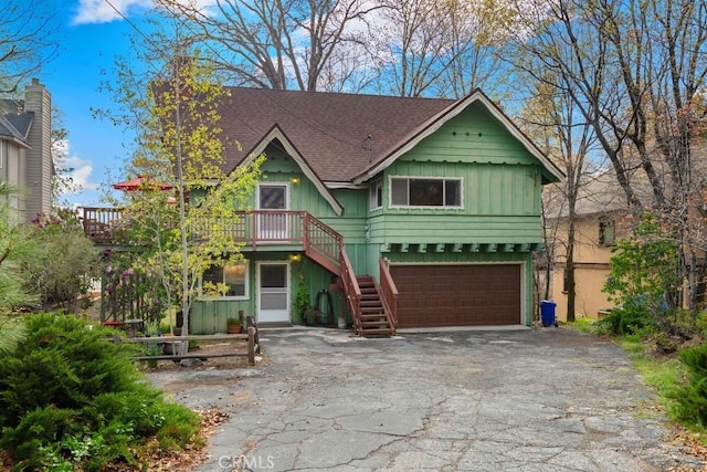view of front facade with stairway, asphalt driveway, an attached garage, board and batten siding, and a shingled roof