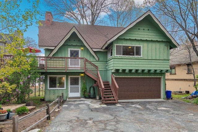 view of front facade with a shingled roof, driveway, stairs, board and batten siding, and a garage