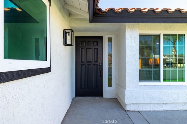 doorway to property featuring stucco siding