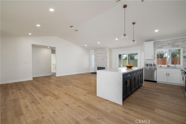 kitchen with stainless steel appliances, light countertops, white cabinets, lofted ceiling, and recessed lighting