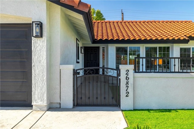 doorway to property featuring a gate, stucco siding, fence, and a tile roof