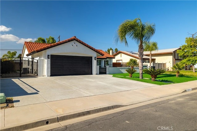 mediterranean / spanish home featuring a gate, an attached garage, stucco siding, a tiled roof, and driveway