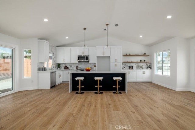 kitchen featuring appliances with stainless steel finishes, a sink, vaulted ceiling, decorative backsplash, and a breakfast bar