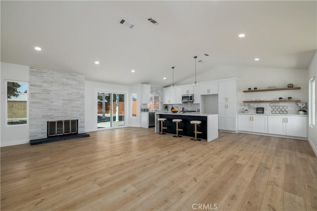kitchen featuring appliances with stainless steel finishes, open floor plan, lofted ceiling, white cabinetry, and a breakfast bar