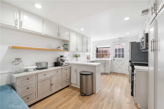9735 Reseda Blvd Unit 56, Northridge, CA 91324 - kitchen with stainless steel microwave, a peninsula, light wood-type flooring, decorative backsplash, and recessed lighting