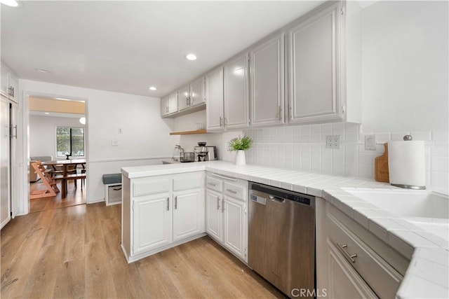 9735 Reseda Blvd Unit 56, Northridge, CA 91324 - kitchen with stainless steel dishwasher, tile countertops, a peninsula, light wood-type flooring, and tasteful backsplash