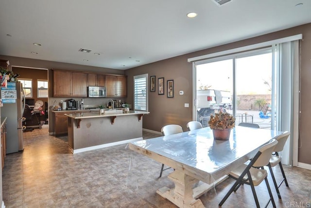 kitchen with stainless steel appliances, a kitchen island with sink, light countertops, recessed lighting, and a breakfast bar area