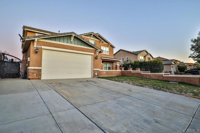 view of front facade featuring stone siding, board and batten siding, concrete driveway, a garage, and fence