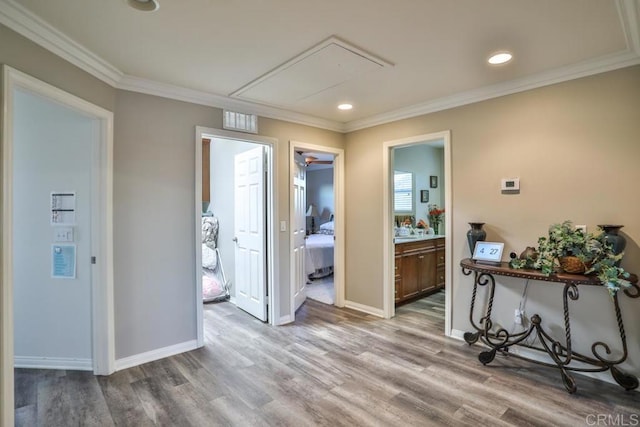 hallway with attic access, wood finished floors, ornamental molding, baseboards, and recessed lighting