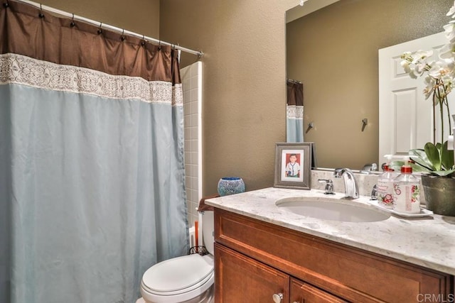 bathroom featuring toilet, a shower with shower curtain, vanity, and a textured wall