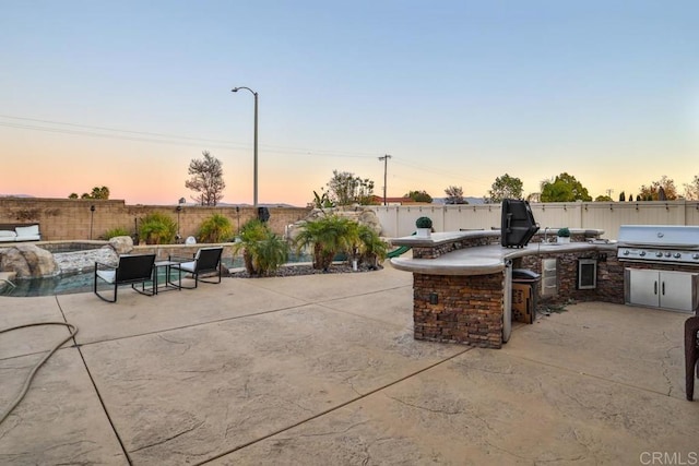 view of patio / terrace with an outdoor kitchen, a fenced backyard, a grill, and exterior bar