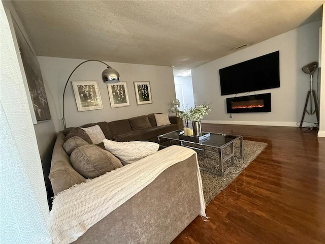 9617 Greenwood Ave, Montclair, CA 91763 - living room with wood finished floors, a textured ceiling, a glass covered fireplace, and baseboards