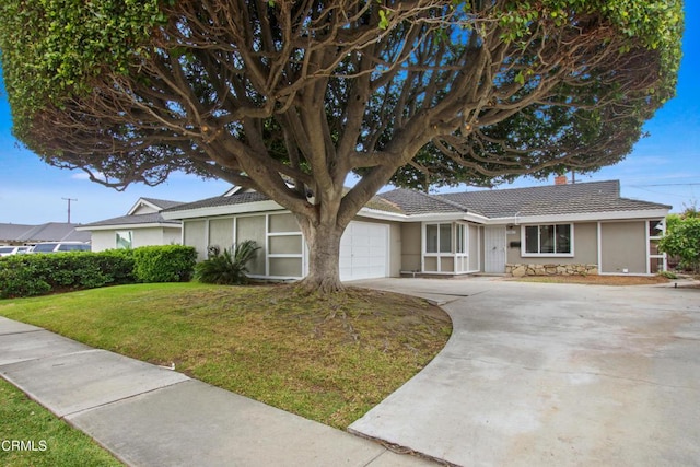 ranch-style house with concrete driveway, a chimney, an attached garage, a front yard, and stucco siding